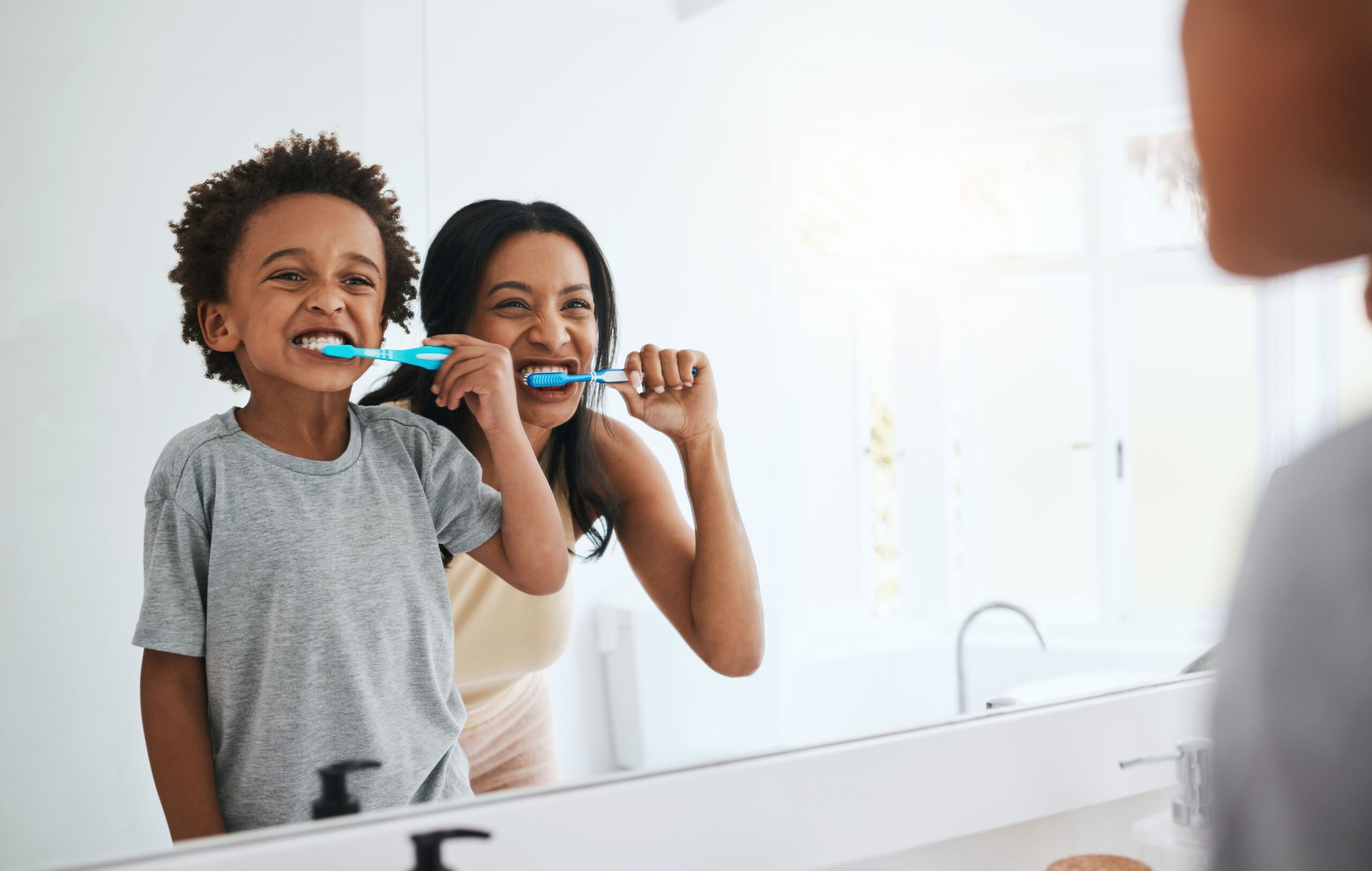 mother and daughter brushing their teeth in the mirror